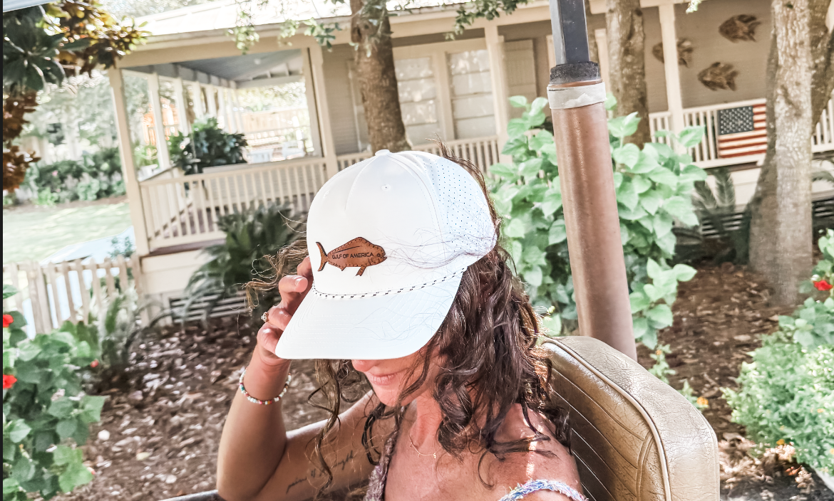 Woman wearing a white Saltgrain Co. Gulf of America patch cap outdoors